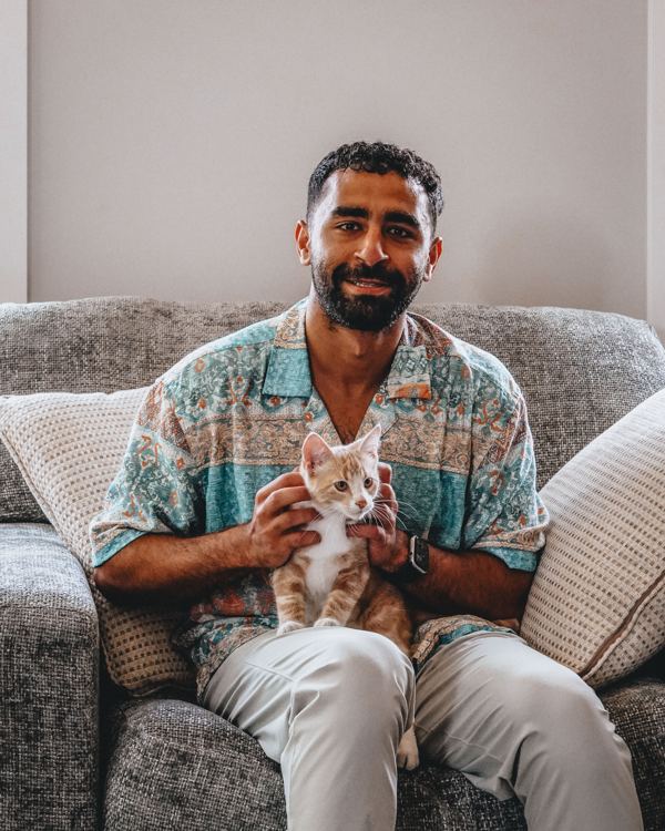Abdel seated on a couch holding a kitten